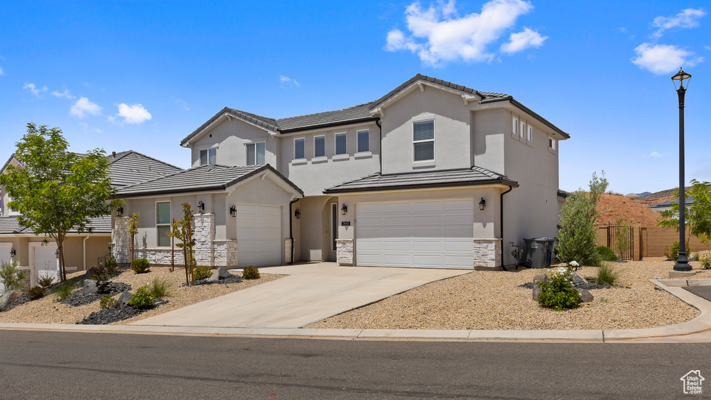Traditional-style house featuring stucco siding, stone siding, an attached garage, concrete driveway, and a tiled roof