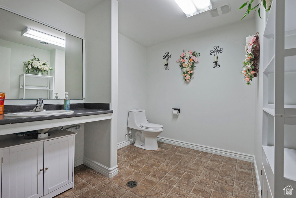 Bathroom with stone finish flooring, baseboards, toilet, and vanity