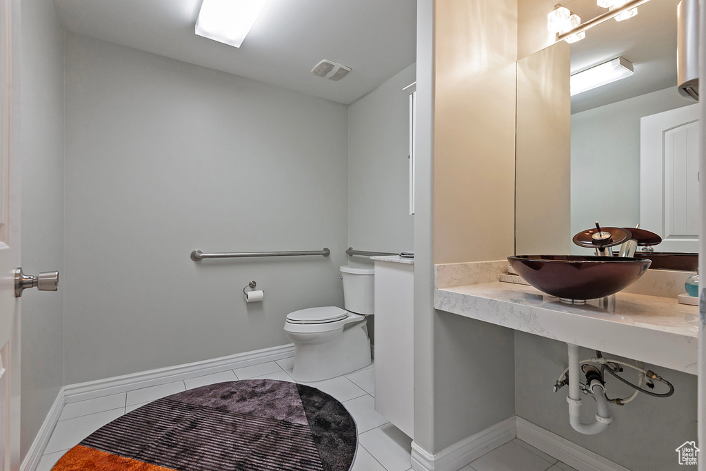 Half bathroom with a sink, toilet, tile patterned flooring, and baseboards