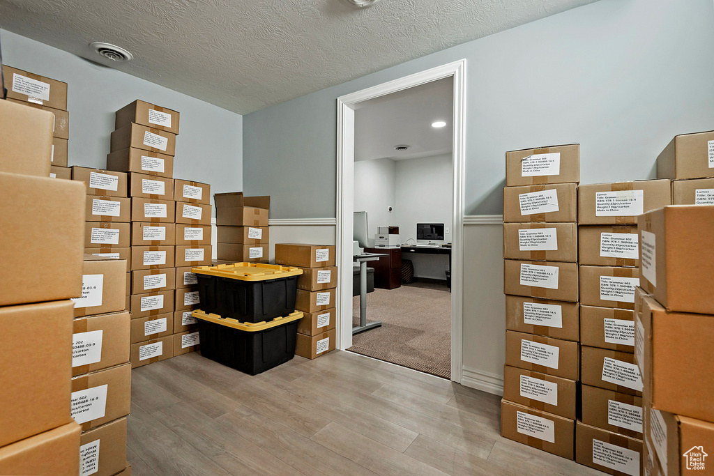 Office space featuring light wood-type flooring and a textured ceiling