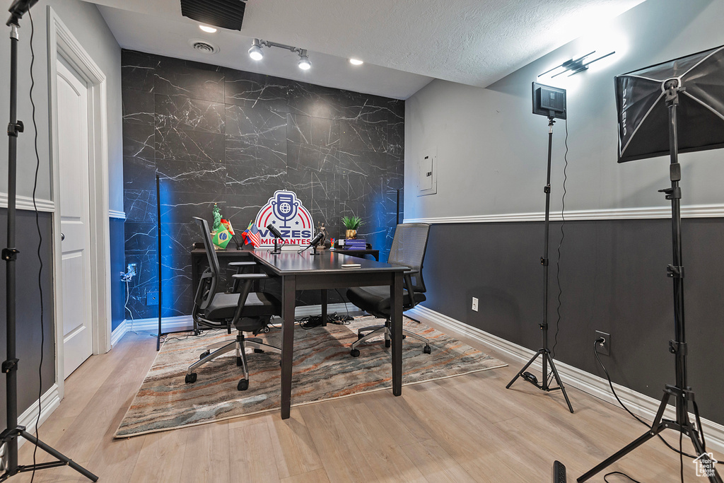 Office area with an accent wall, wood finished floors, baseboards, and a textured ceiling