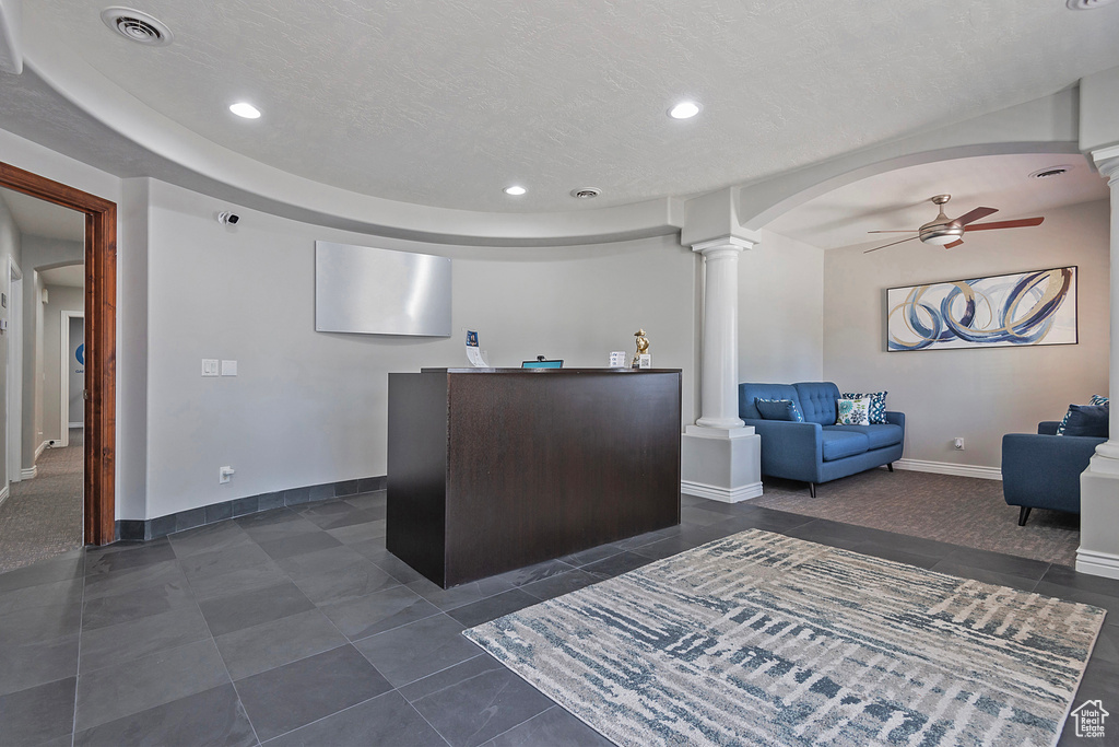 Reception area with decorative columns, a ceiling fan, arched walkways, and recessed lighting