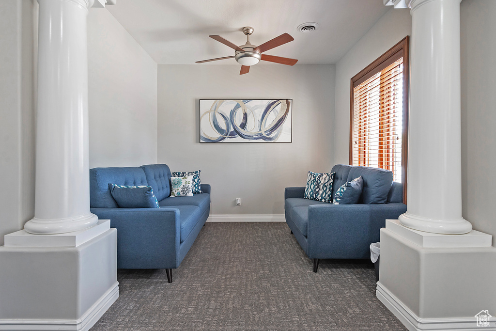 Living room with ornate columns, carpet flooring, and a ceiling fan