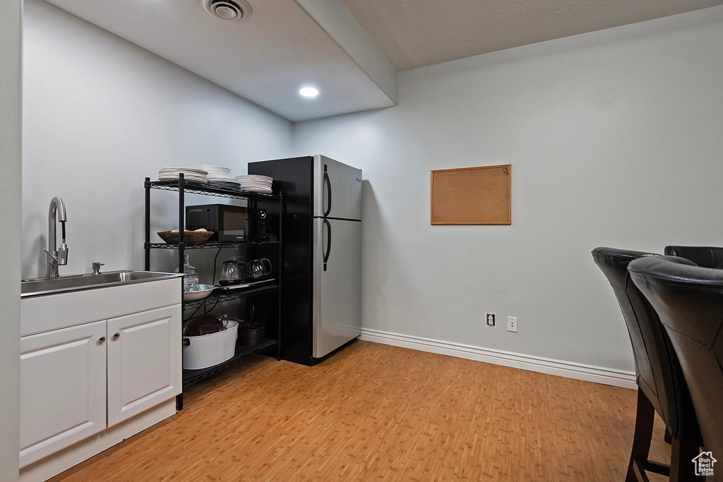 Office space featuring a sink, light wood finished floors, baseboards, and recessed lighting