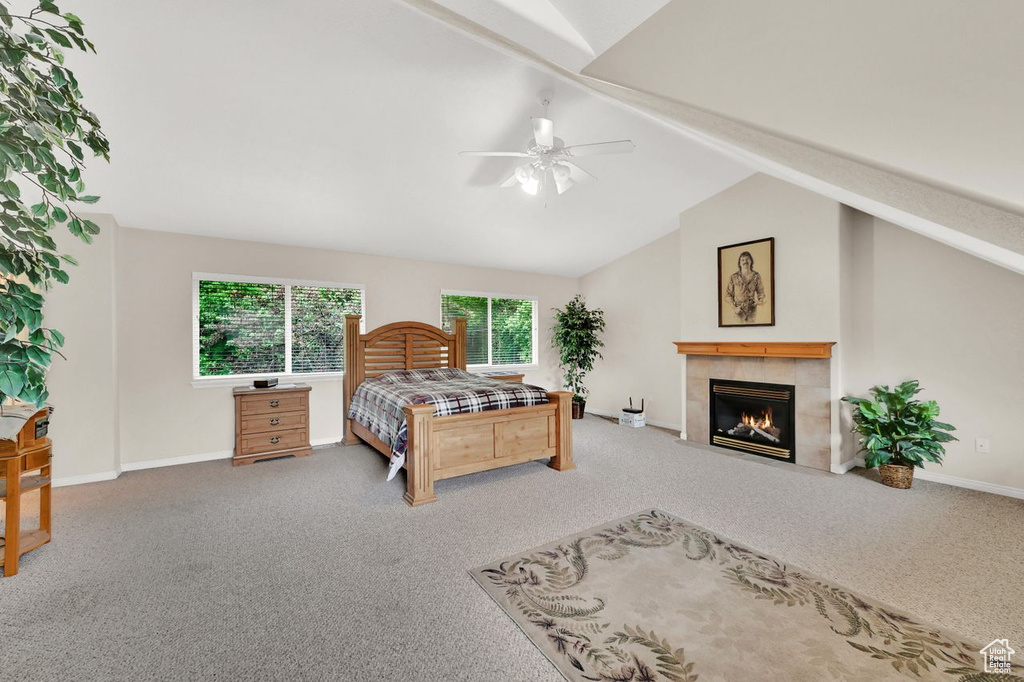 Carpeted bedroom with baseboards, a tiled fireplace, and a ceiling fan