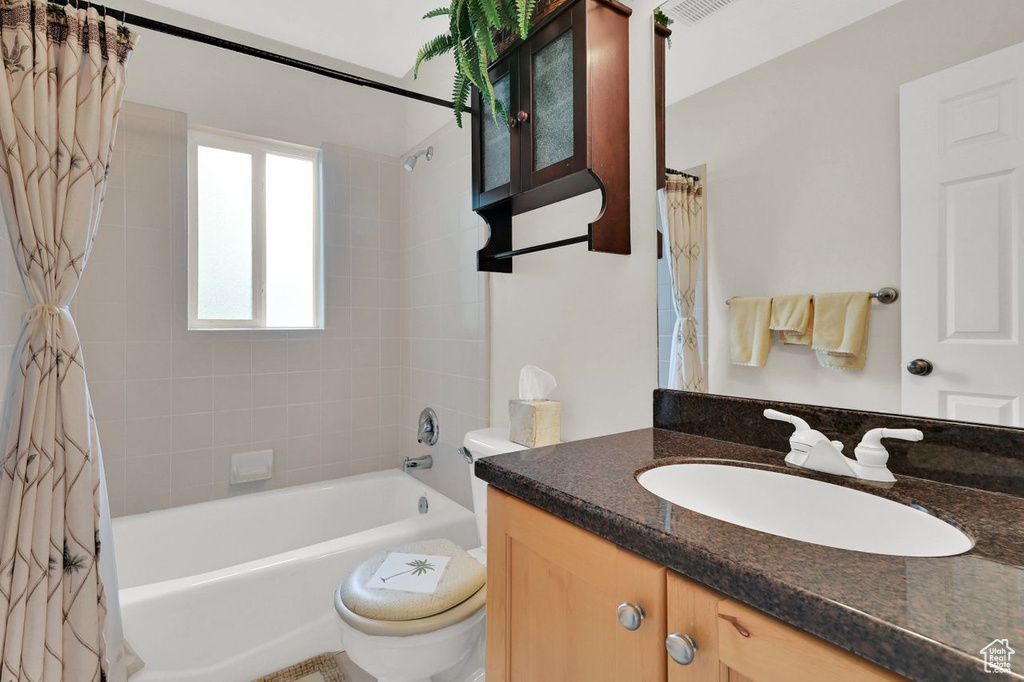 Bathroom featuring toilet, shower / bath combination with curtain, and vanity