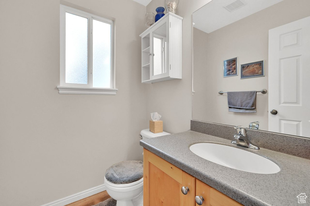 Half bath featuring toilet, vanity, and baseboards