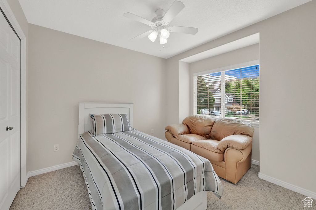 Bedroom with light colored carpet, baseboards, and ceiling fan