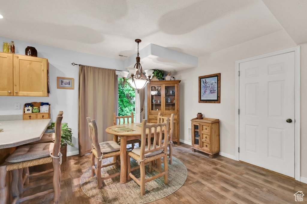 Dining room featuring a chandelier, light wood-type flooring, and baseboards