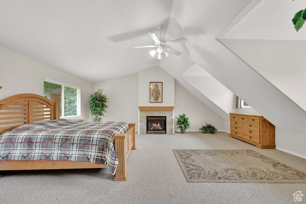 Bedroom with carpet floors, lofted ceiling, ceiling fan, and a tile fireplace