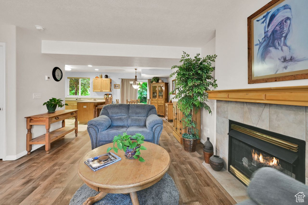 Living room with wood finished floors, a tile fireplace, and baseboards