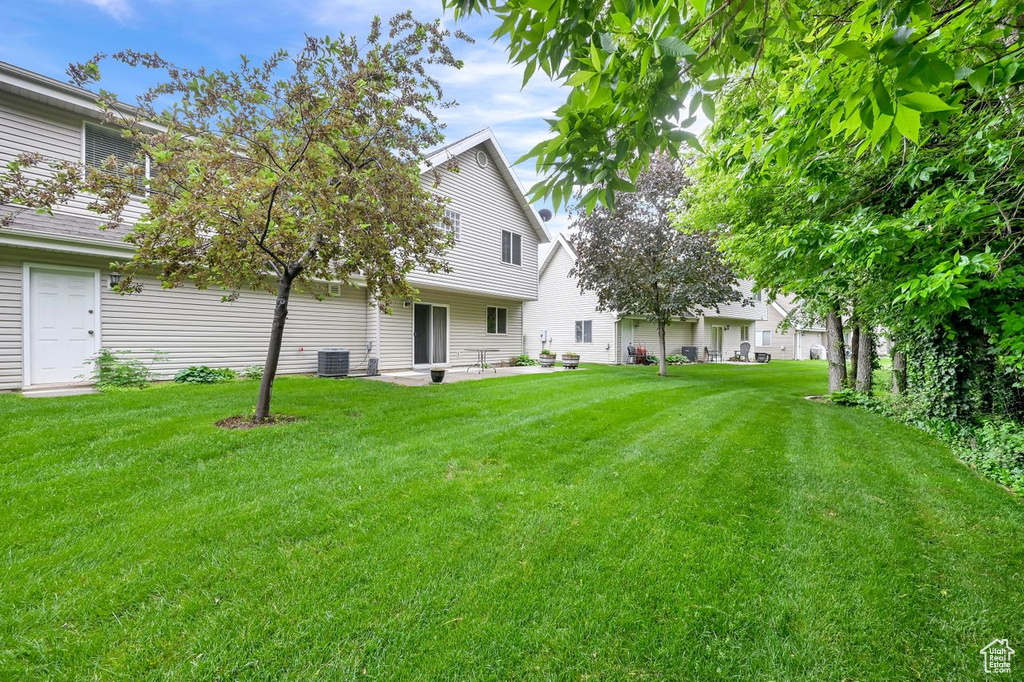 View of grassy yard featuring a patio area and central AC