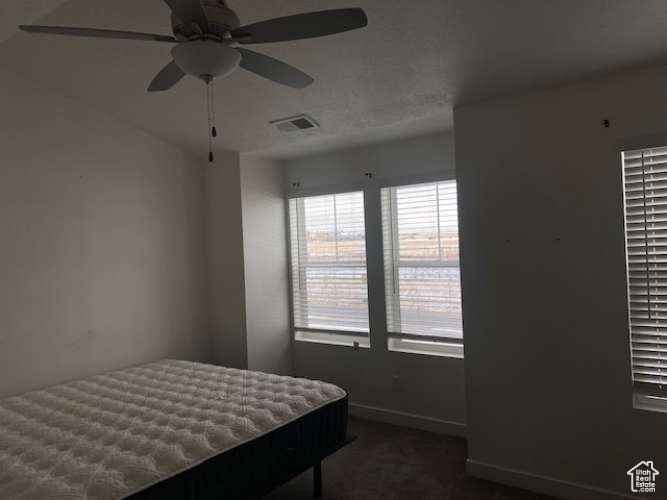 Bedroom featuring baseboards, dark carpet, and ceiling fan