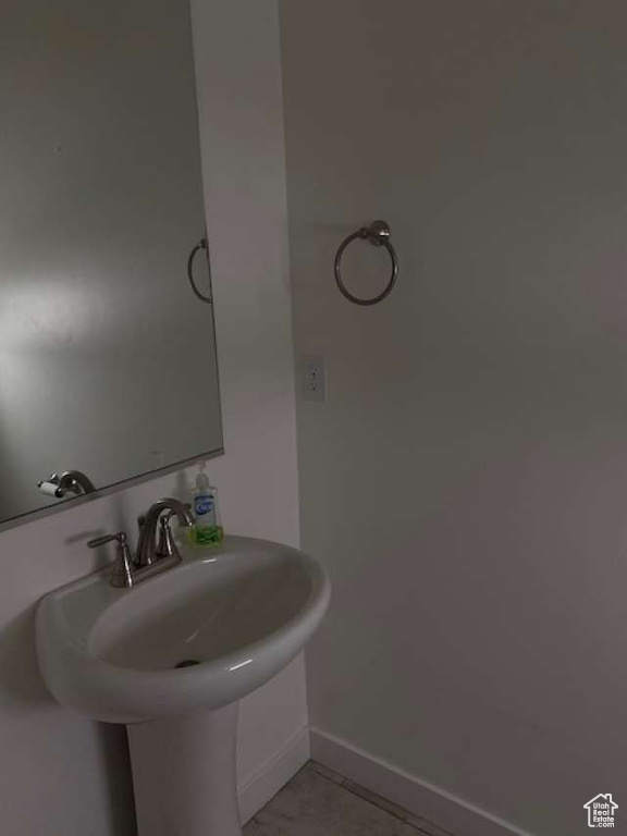 Bathroom featuring baseboards, tile patterned floors, and a sink