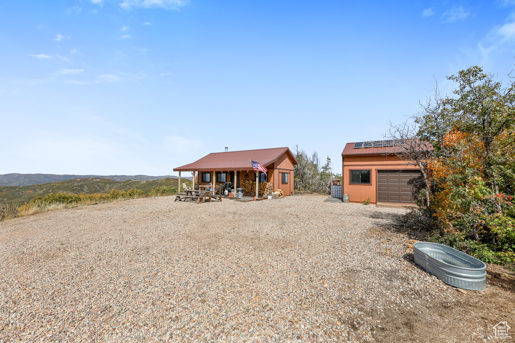 Rear view of house with roof mounted solar panels, an outbuilding, and a porch