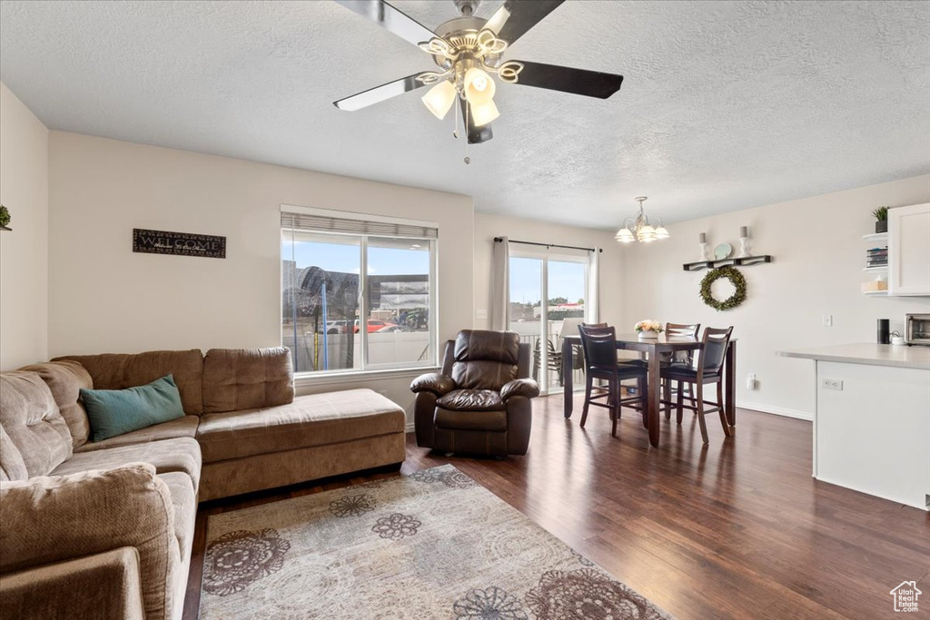 Living area featuring a chandelier, a textured ceiling, dark wood-style flooring, and ceiling fan