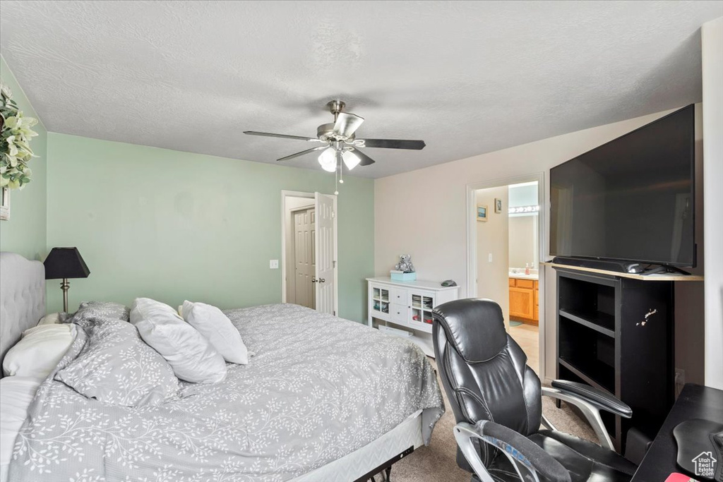 Carpeted bedroom featuring ceiling fan and ensuite bath