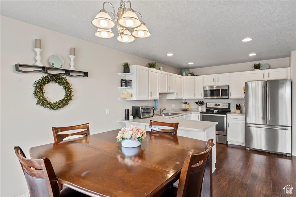 Dining area with a chandelier, recessed lighting, dark wood-style flooring, and a textured ceiling