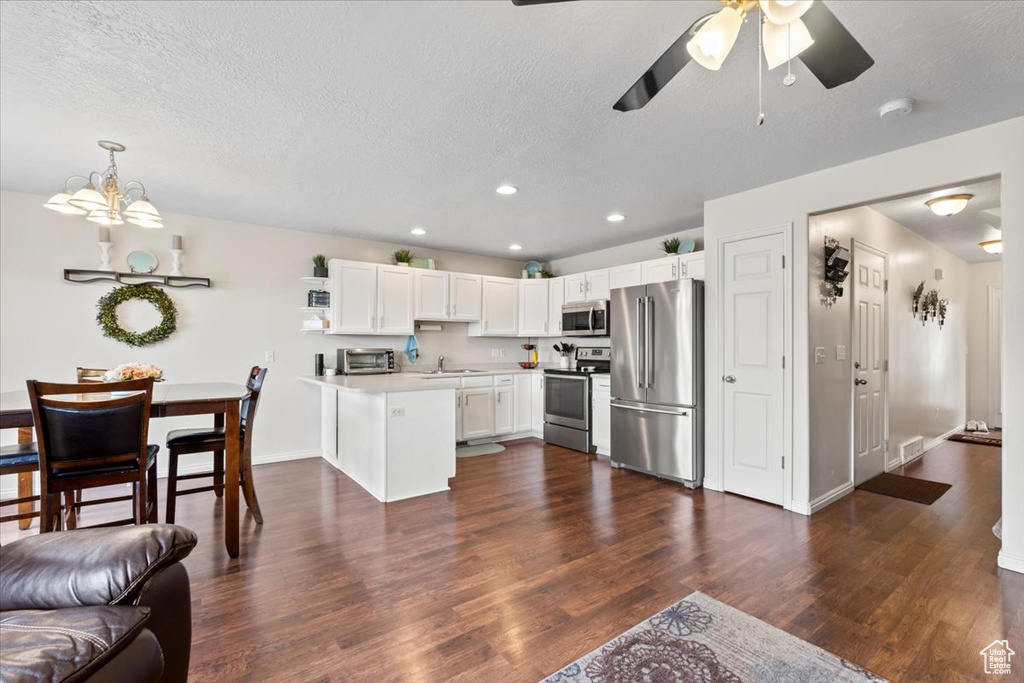 Kitchen with stainless steel appliances, a peninsula, a sink, light countertops, and a textured ceiling