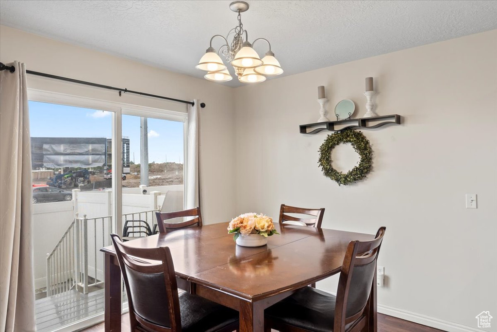 Dining room with a chandelier, a textured ceiling, and wood finished floors