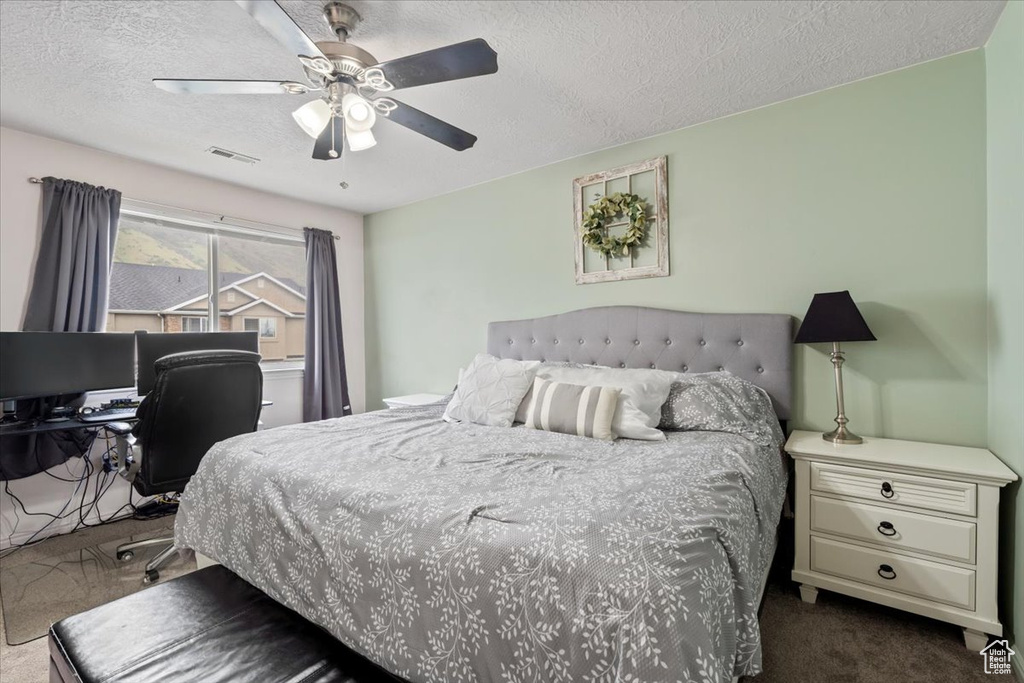 Bedroom featuring dark carpet, a textured ceiling, and a ceiling fan