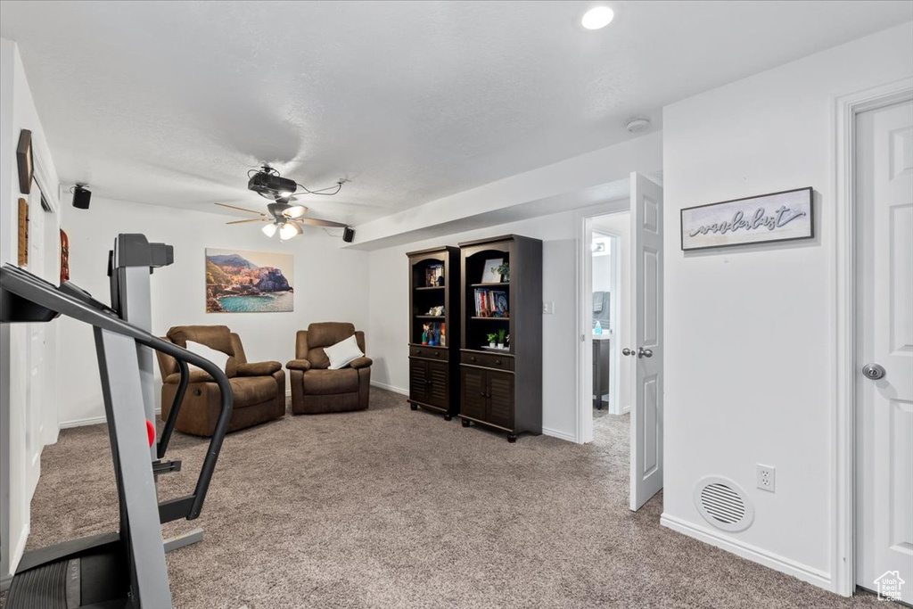 Exercise room with carpet flooring, a ceiling fan, and baseboards