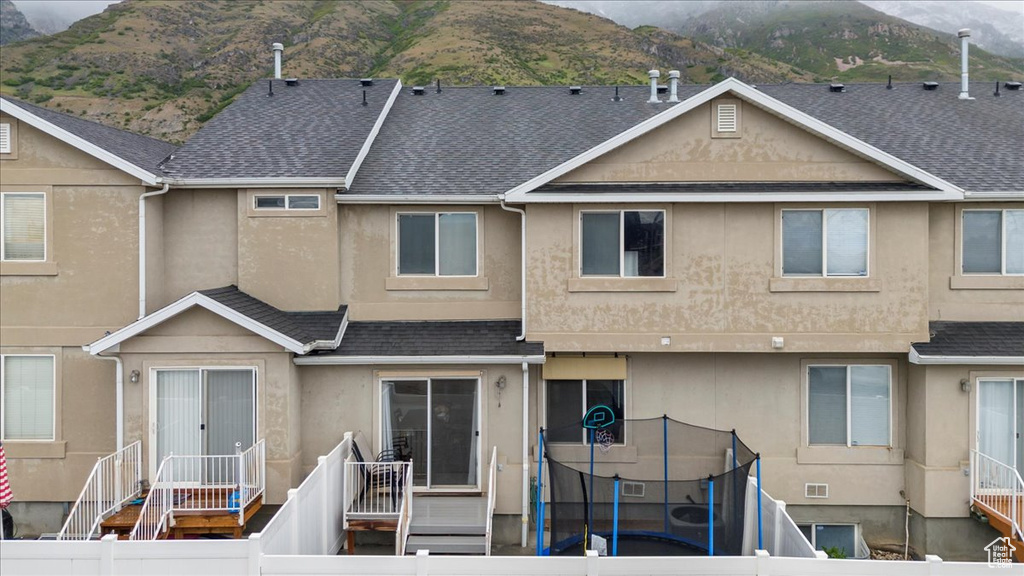 Rear view of house featuring stucco siding, a mountain view, and roof with shingles