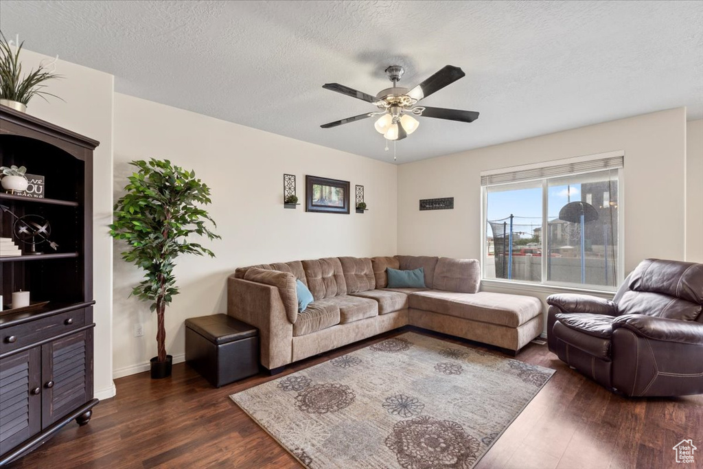 Living area featuring dark wood finished floors, ceiling fan, a textured ceiling, and baseboards
