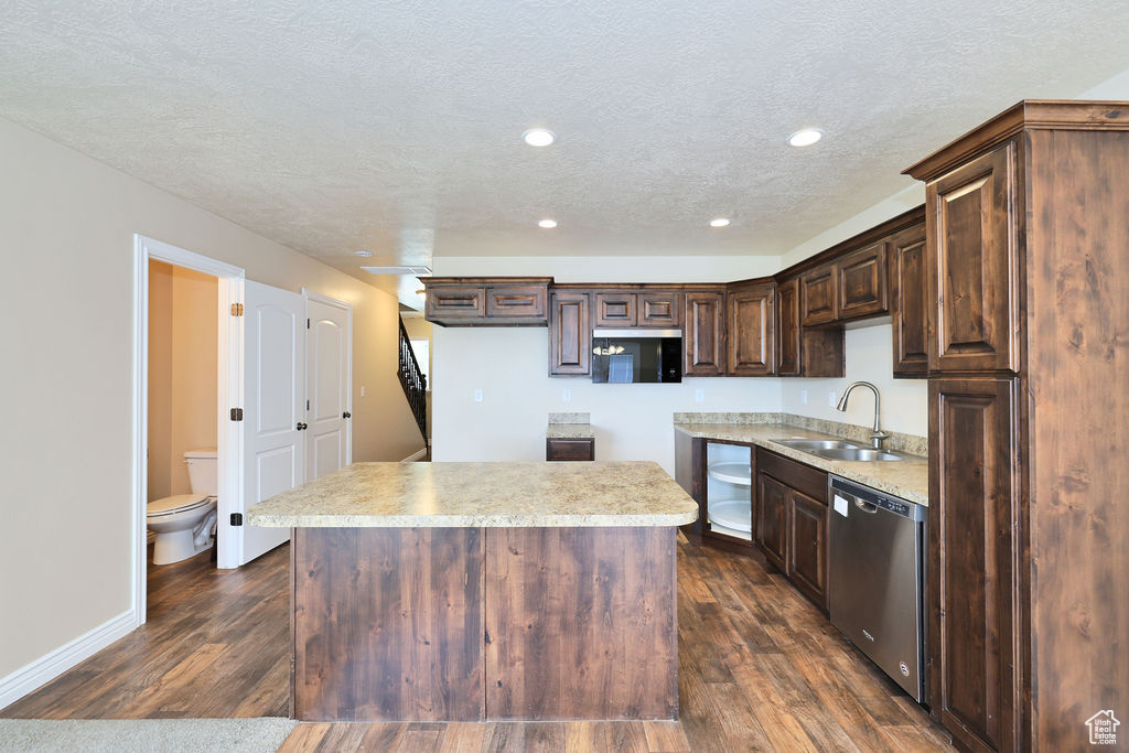 Kitchen featuring stainless steel dishwasher, a sink, dark brown cabinetry, a kitchen island, and a textured ceiling
