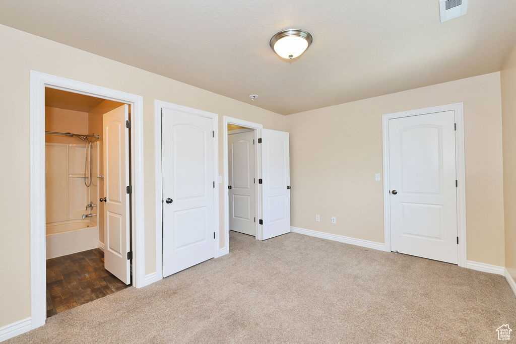 Unfurnished bedroom featuring carpet flooring, baseboards, and ensuite bathroom