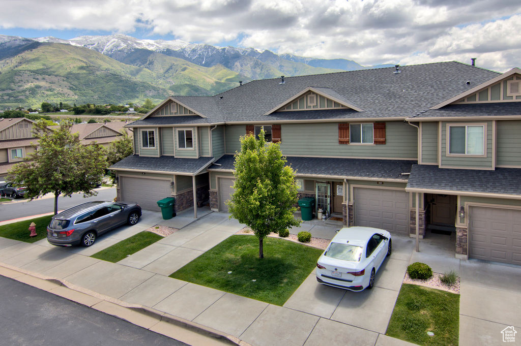 View of front of home featuring driveway, an attached garage, a mountain view, and a shingled roof