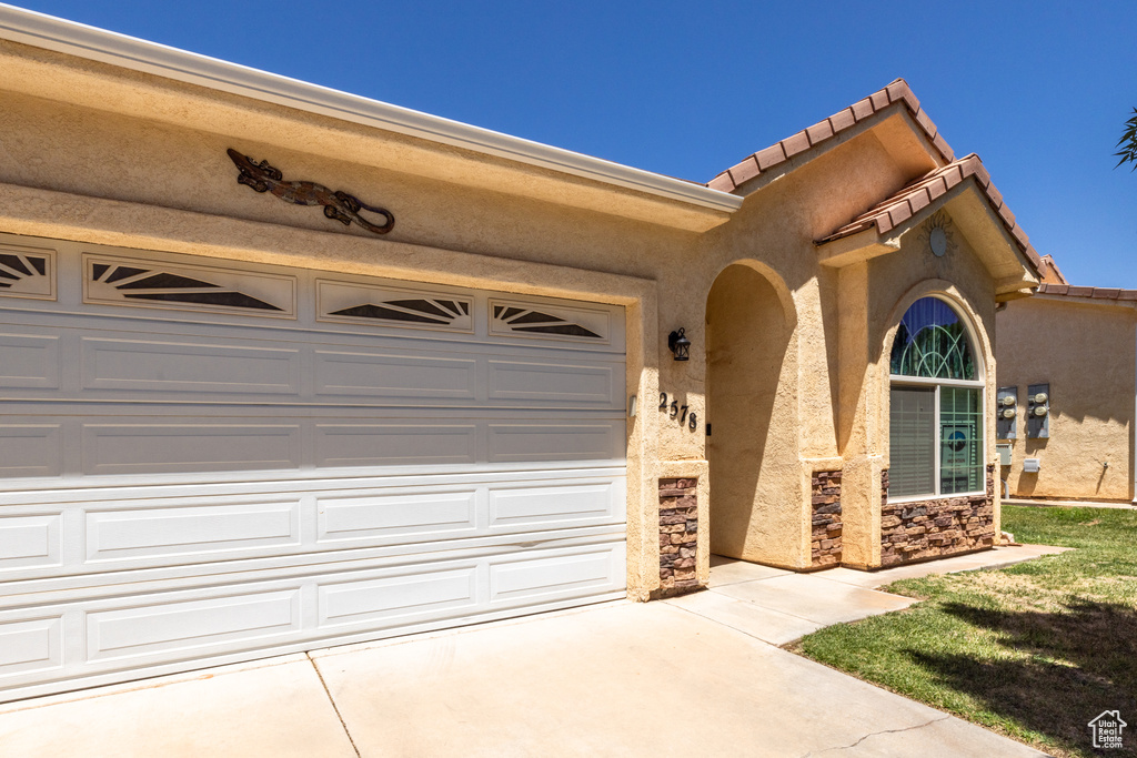 View of front of house featuring concrete driveway, stucco siding, an attached garage, a tile roof, and stone siding
