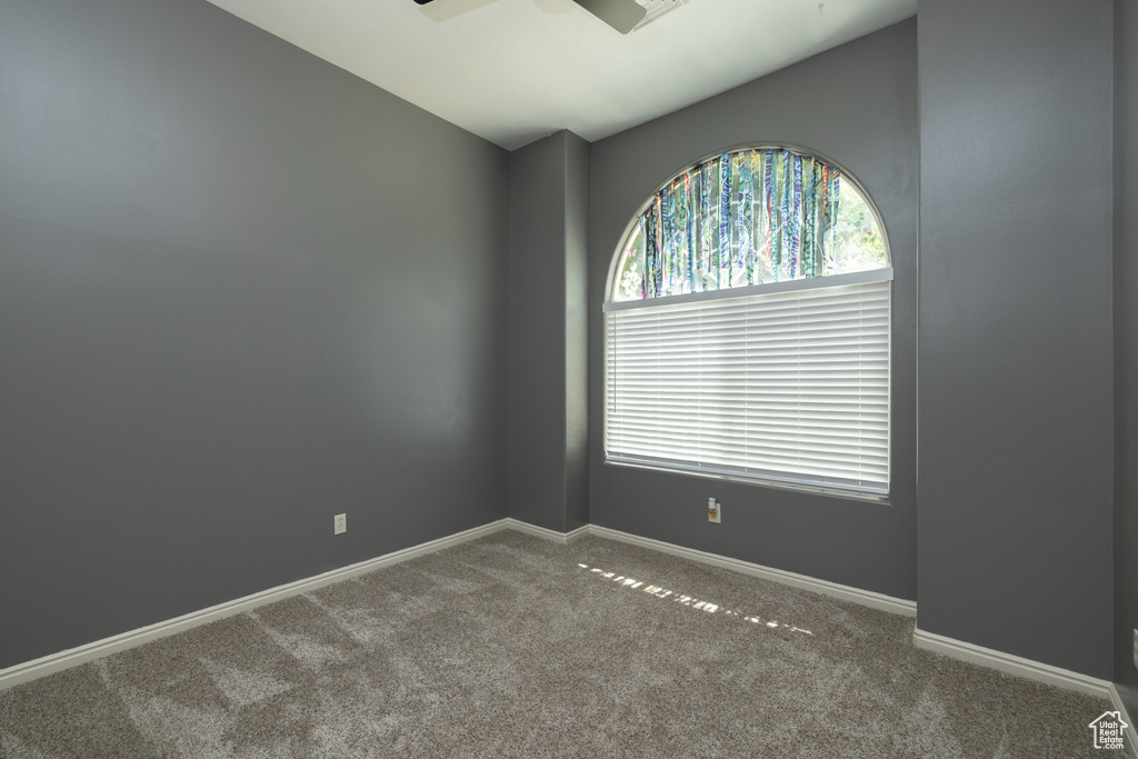 Spare room featuring carpet floors, a ceiling fan, vaulted ceiling, and baseboards