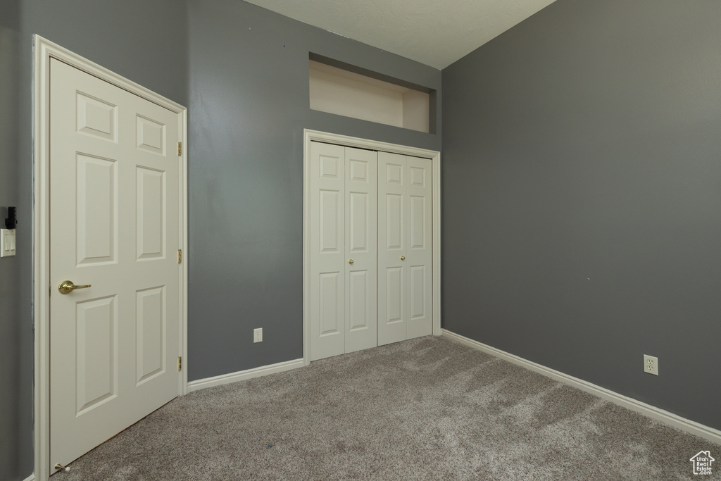 Unfurnished bedroom with carpet floors, a closet, and baseboards