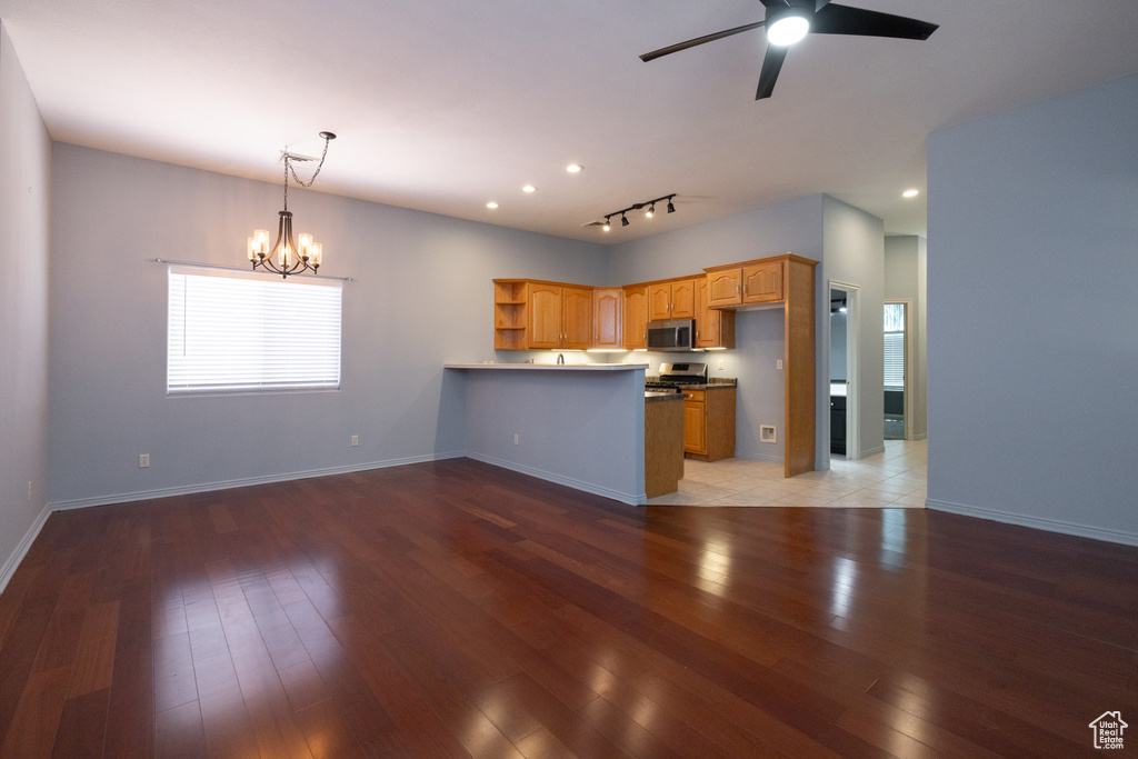 Kitchen with stainless steel microwave, a peninsula, a chandelier, open shelves, and light wood-style floors