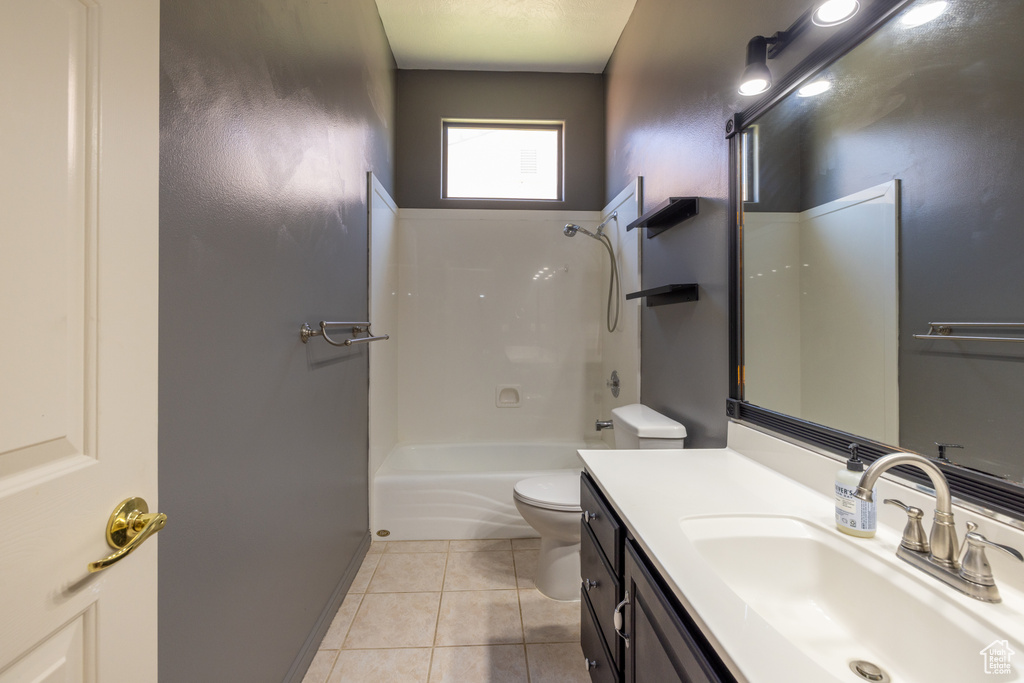 Bathroom with toilet, vanity, tile patterned flooring, shower / washtub combination, and baseboards