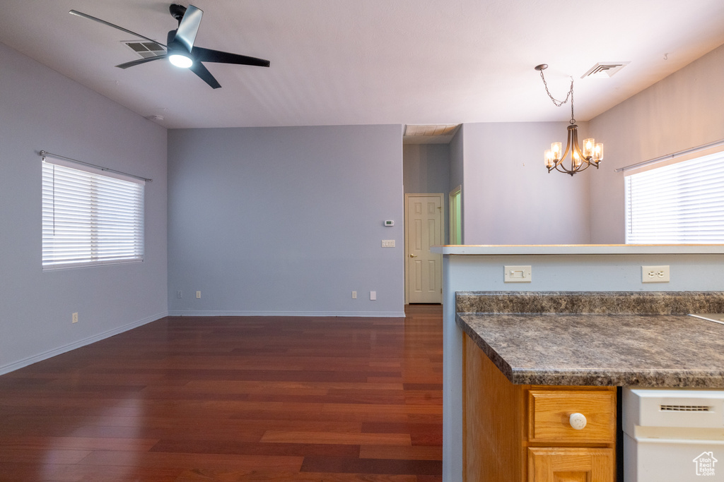 Kitchen with dark wood-type flooring, a chandelier, a ceiling fan, dark countertops, and plenty of natural light
