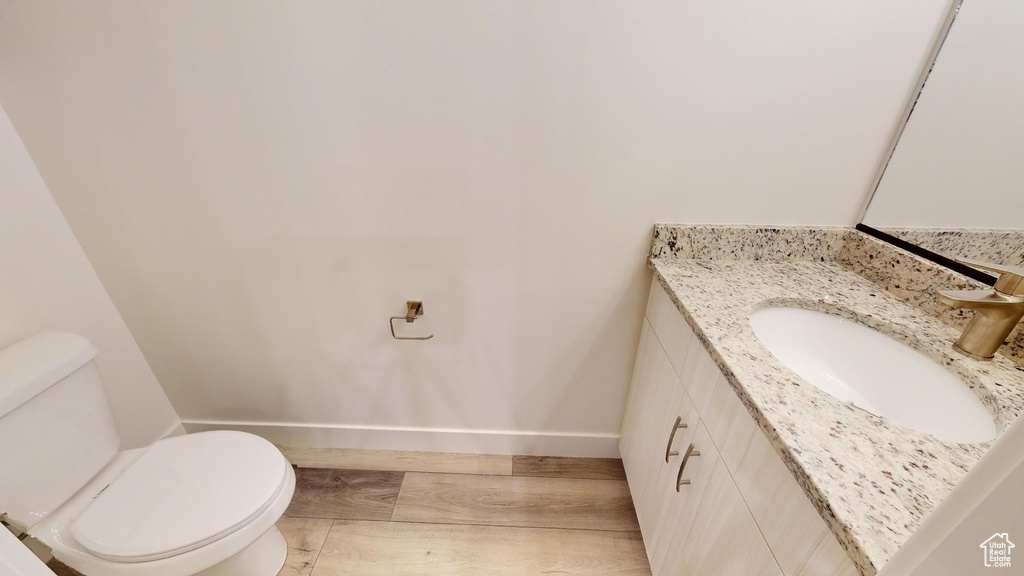 Bathroom featuring wood finished floors, toilet, baseboards, and vanity