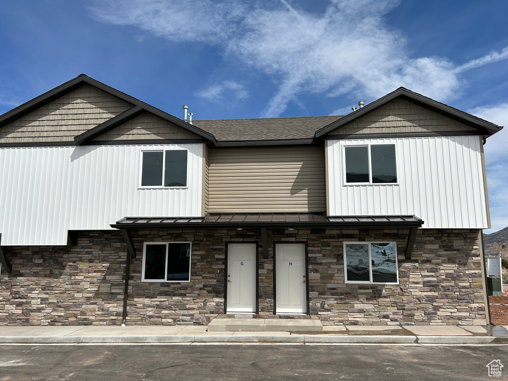 View of front of property with stone siding, a standing seam roof, and metal roof