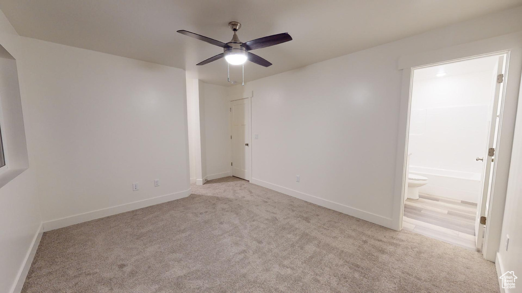 Carpeted spare room with a ceiling fan, arched walkways, and baseboards