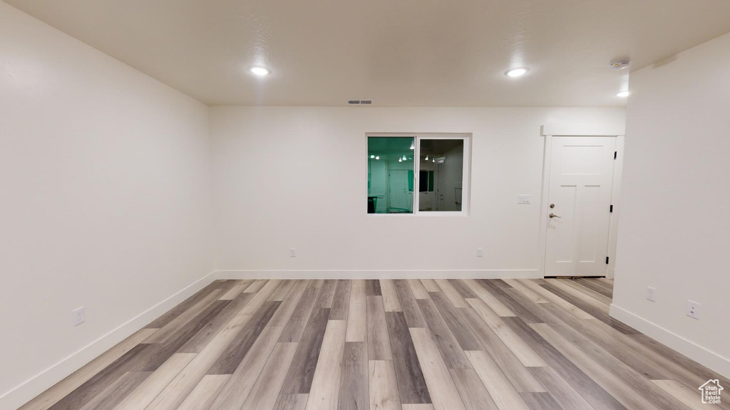 Empty room featuring light wood-style floors, baseboards, recessed lighting, and a smoke detector