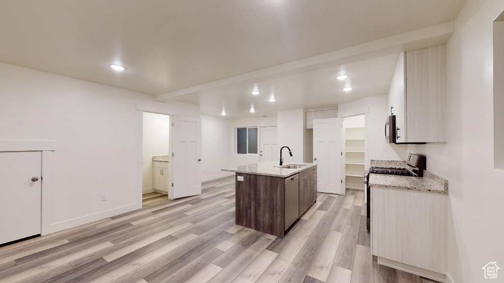 Kitchen with appliances with stainless steel finishes, light wood-style flooring, a sink, a center island with sink, and recessed lighting