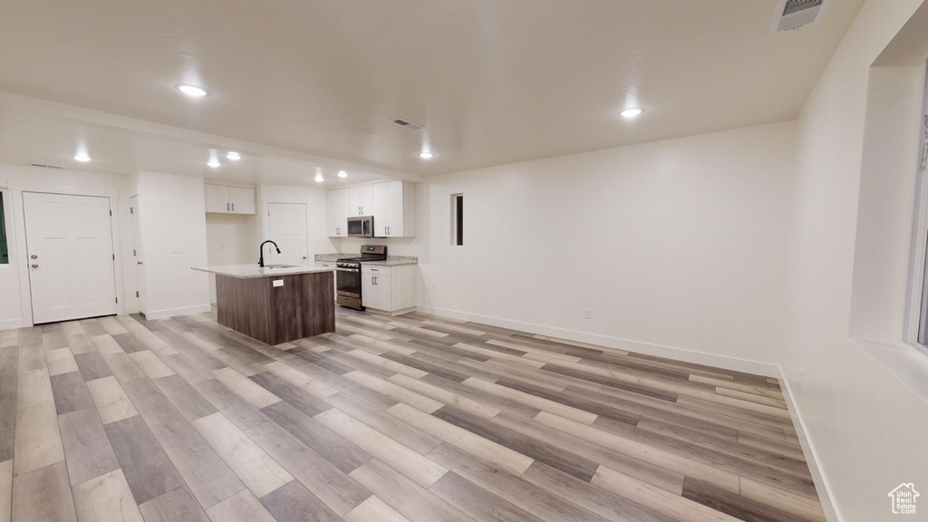 Kitchen featuring stainless steel appliances, a sink, recessed lighting, white cabinetry, and light countertops
