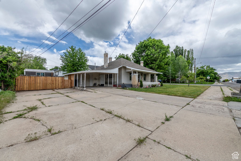 View of front of home with concrete driveway, covered porch, and a chimney
