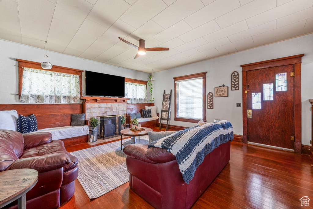 Living room featuring a ceiling fan, wood finished floors, a glass covered fireplace, and baseboards