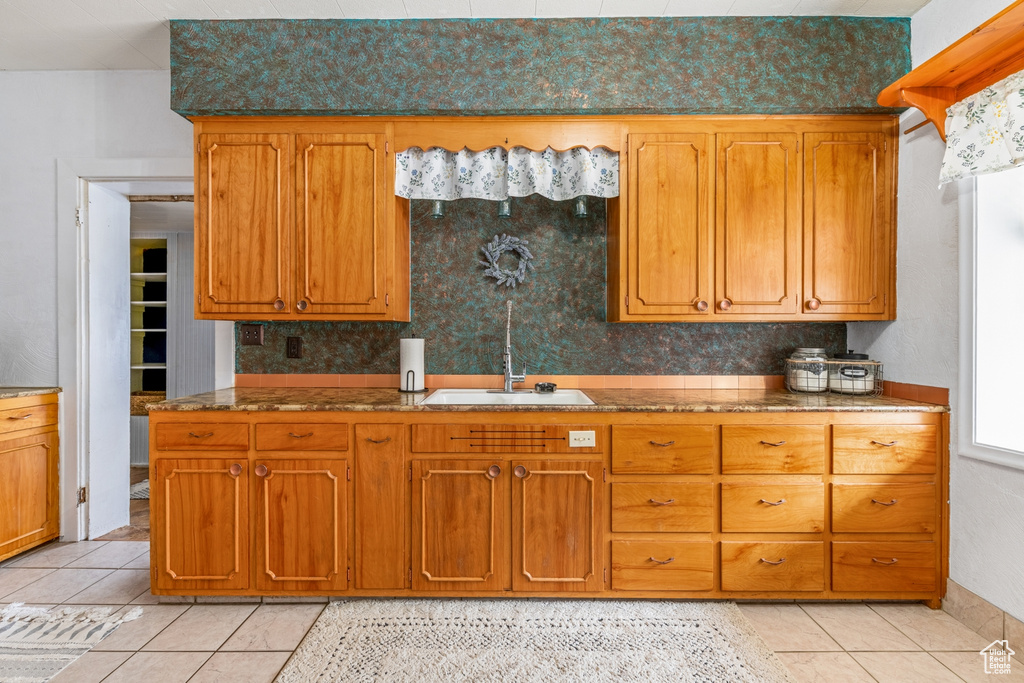 Kitchen featuring a sink, light tile patterned floors, and brown cabinets