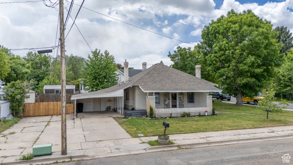 View of front of property featuring concrete driveway, brick siding, an attached carport, roof with shingles, and a porch