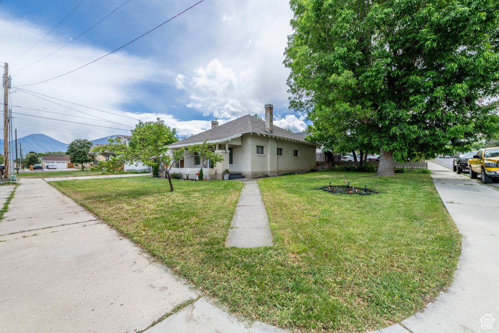 View of front of home featuring a front yard, a mountain view, and a chimney