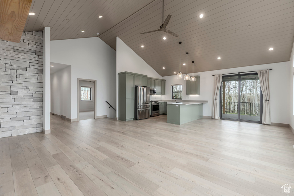 Unfurnished living room featuring baseboards, high vaulted ceiling, light wood-style flooring, a ceiling fan, and recessed lighting