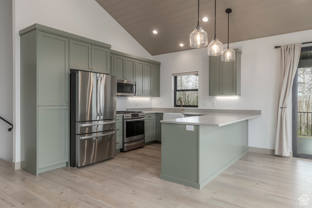 Kitchen with stainless steel appliances, a peninsula, light countertops, light wood-style floors, and recessed lighting